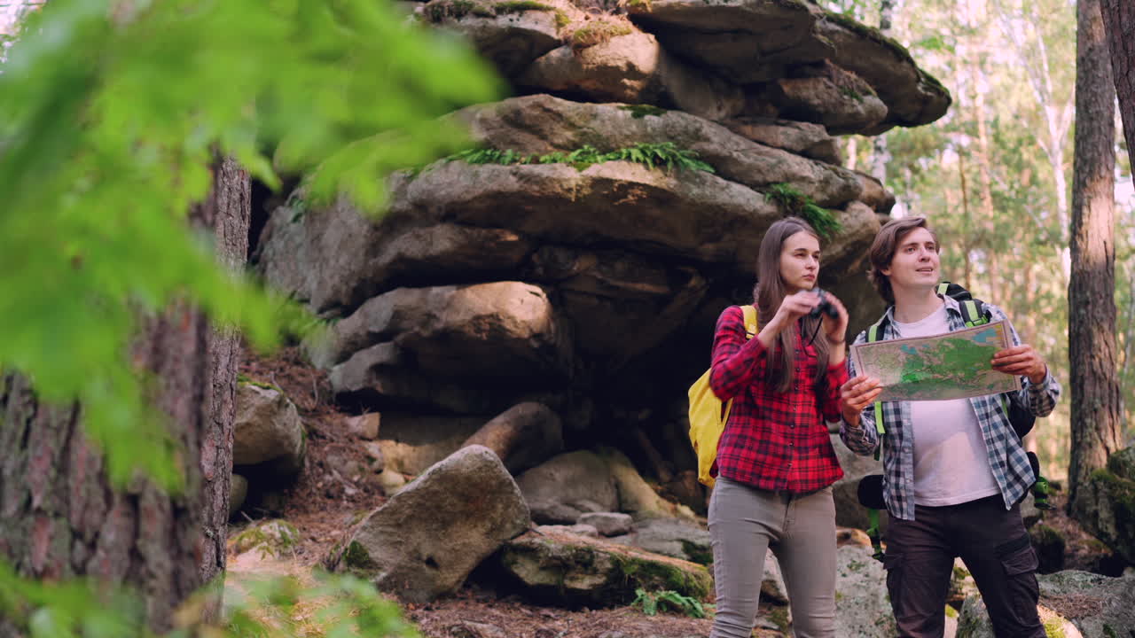 Hikers using a map in a forest with rocks
