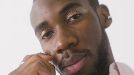 close up male model with make up crying and cleaning his tears