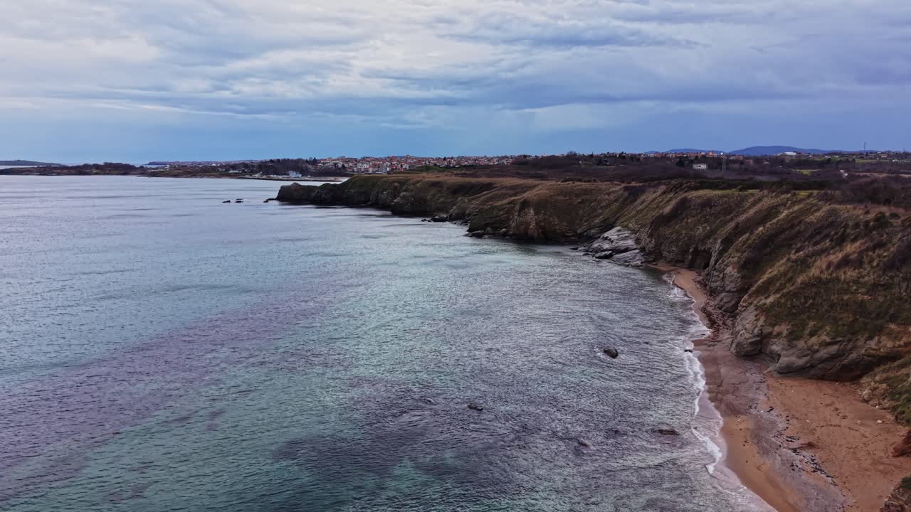 Kystlinje med klipper og strand tæt på vand under skyet vejr