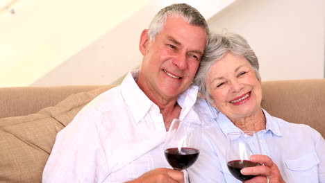 senior couple sitting on couch having red wine