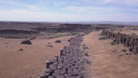 aerial flight along top of arid basalt column cliff in scablands, wa