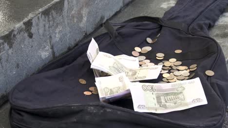 money and coins in a guitar case on the street