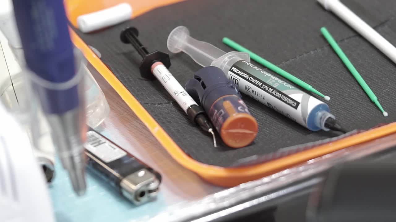 Primo piano di agenti adesivi dentali, siringhe di gel mordenzante e applicatori a micro-spazzola su un vassoio clinico