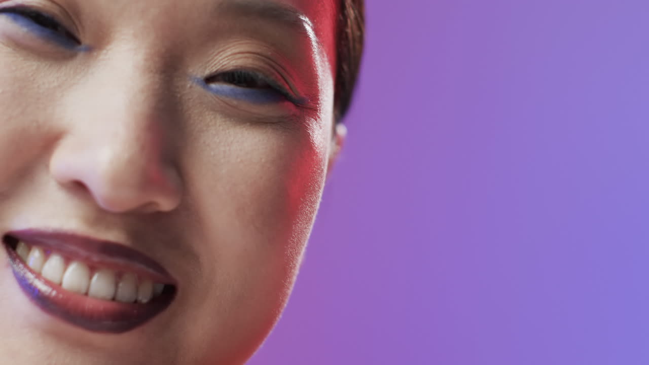mujer asiática con cabello negro y maquillaje sonriendo, copia espacio, cámara lenta