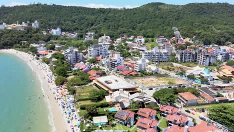 escena aérea de drones de playa turística en florianópolis con muchas casas de verano hoteles frente al mar malla de playa urbana con mucha gente disfrutando del sol, la arena y el mar