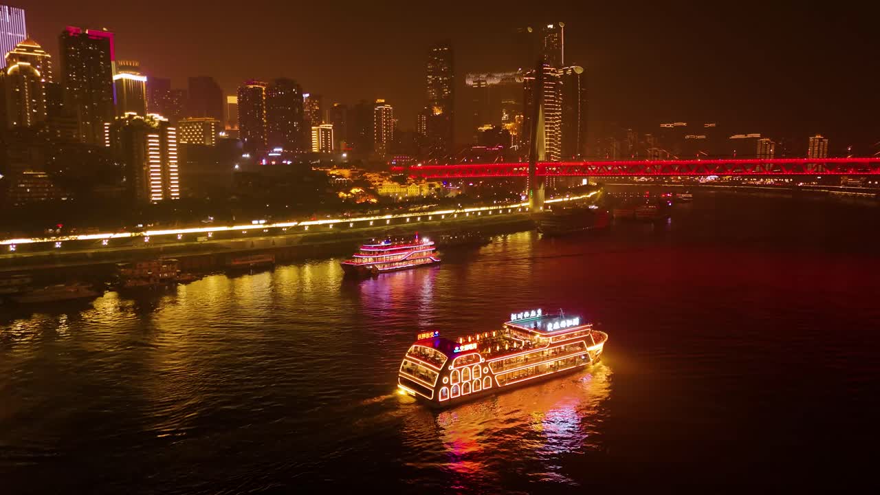 Aerial drone shot of boats cruising on Yangtze River and the Twin River Bridges at night in Chongqing, Yuzhong District, China
