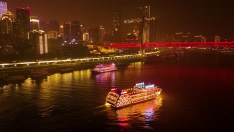 aerial drone shot of boats cruising on yangtze river and the twin river bridges at night in chongqing, yuzhong district, china