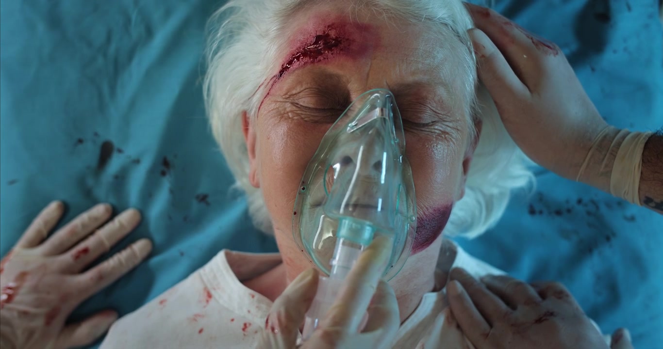 Donna anziana ferita con maschera d'ossigeno al pronto soccorso