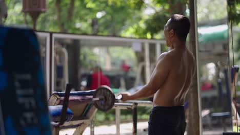 man doing bicep curls with a barbell in an outdoor gym