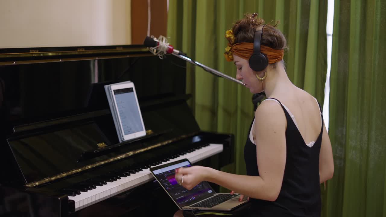 Woman recording music in a studio with a piano and laptop