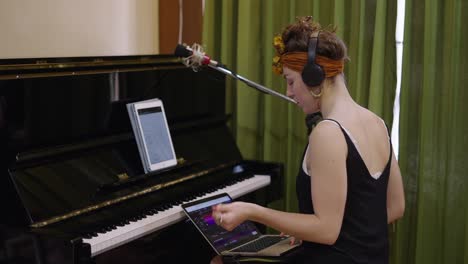 woman recording music in a studio with a piano and laptop