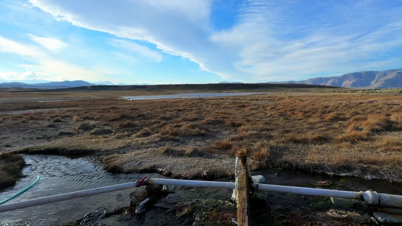 Mammoth lakes Hilltop Wild Willy's natural hot springs water temperature control valve valve pvc piping tube sunny blue sky California Sierra Nevada range slow pan left motion
