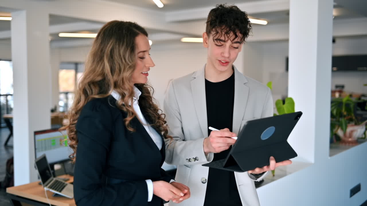 Forretningsmøde på et kontor. En kvinde og en ung mand diskuterer forretningsanliggender med en tablet. Slowmotion.