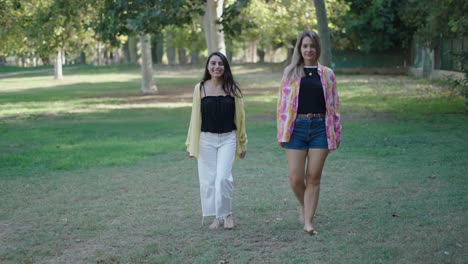 two women walking barefoot in a park
