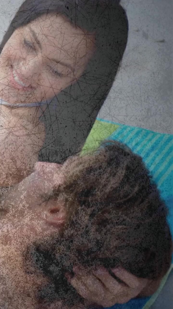Vertical video: Shot showing man leaning over man on towel, cradling hair, overlay moving, health