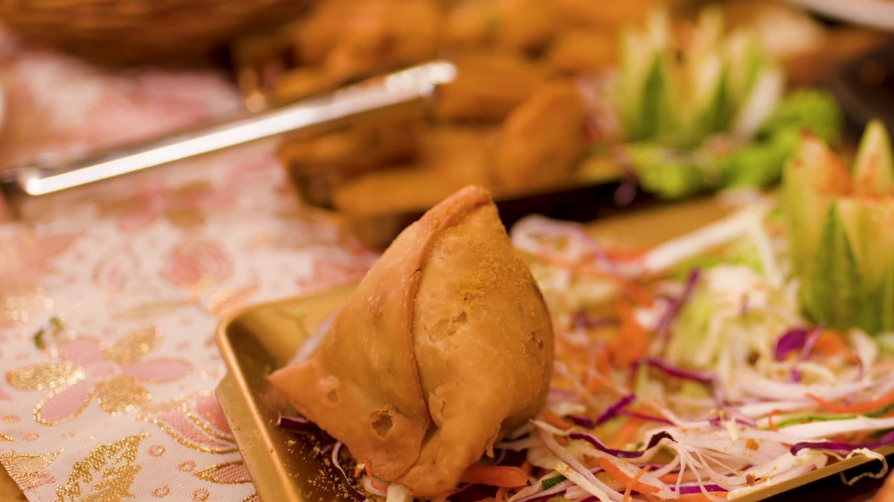 Mano che usa le pinze per prendere un samosa croccante