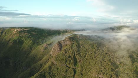 air current moves ground clouds over green mountainous landscape, aerial