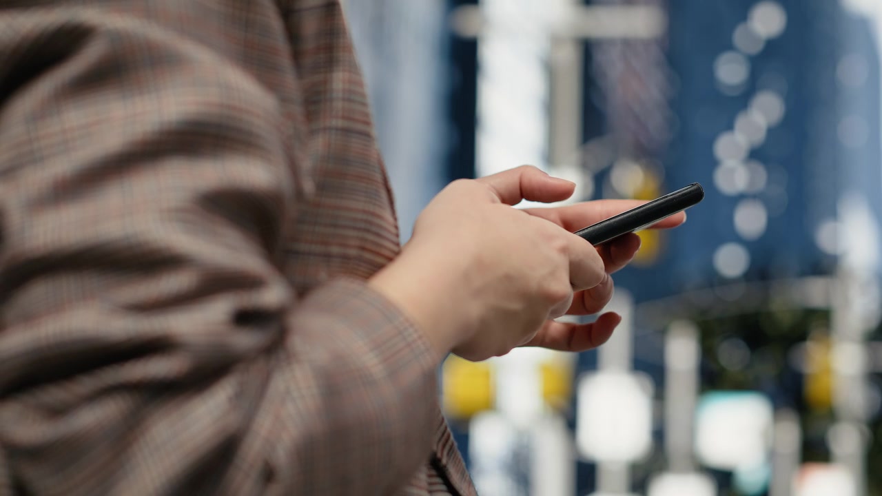 Close up of businessperson using smartphone on city avenue