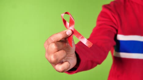 hand holding red hiv ribbon against green screen