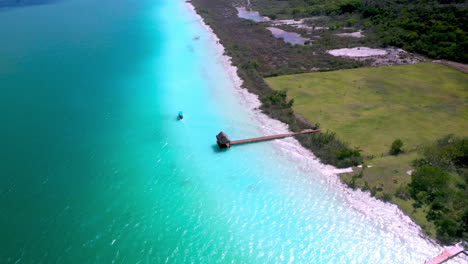 rotating drone shot of piers, docks and boat in turquoise waters at bacalar mexico