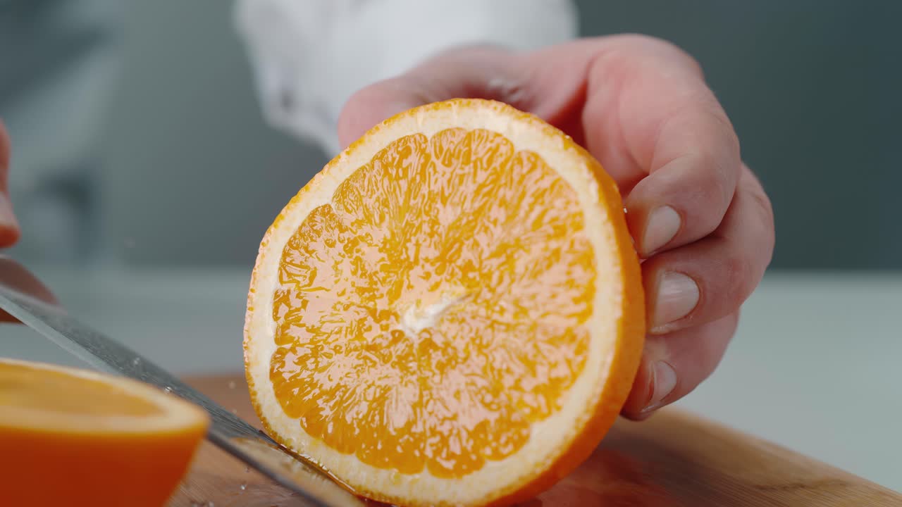 persona cortando naranja en una tabla de cortar de madera