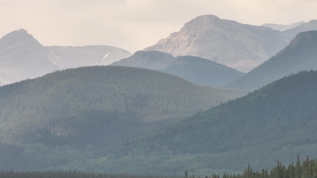 el humo de los incendios forestales oscurece las montañas rocosas mientras un avión no tripulado vuela de izquierda a derecha en alberta, canadá
