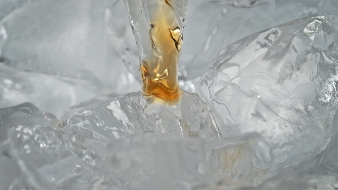 얼음 큐브에 위스키를 는 거대 및 느린 모션에서 버 액체가 얼어붙은 블록 아래로 흐르고 냉각됩니다.