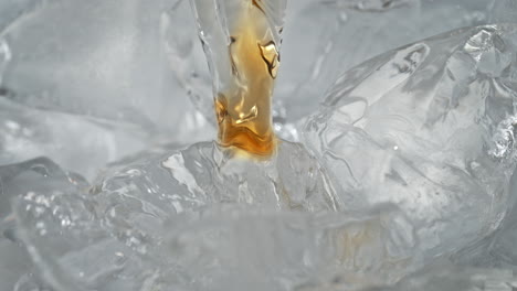 pouring whisky on ice cubes in macro and slow motion, amber liquid flows down the frozen blocks and cools down