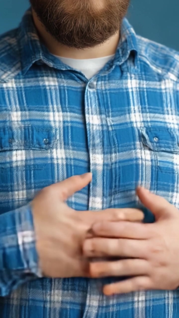 Un uomo con una camicia di flanella blu e la barba, che guarda pensieroso la fotocamera, mostrando espressione ed emozione in un ambiente da studio
