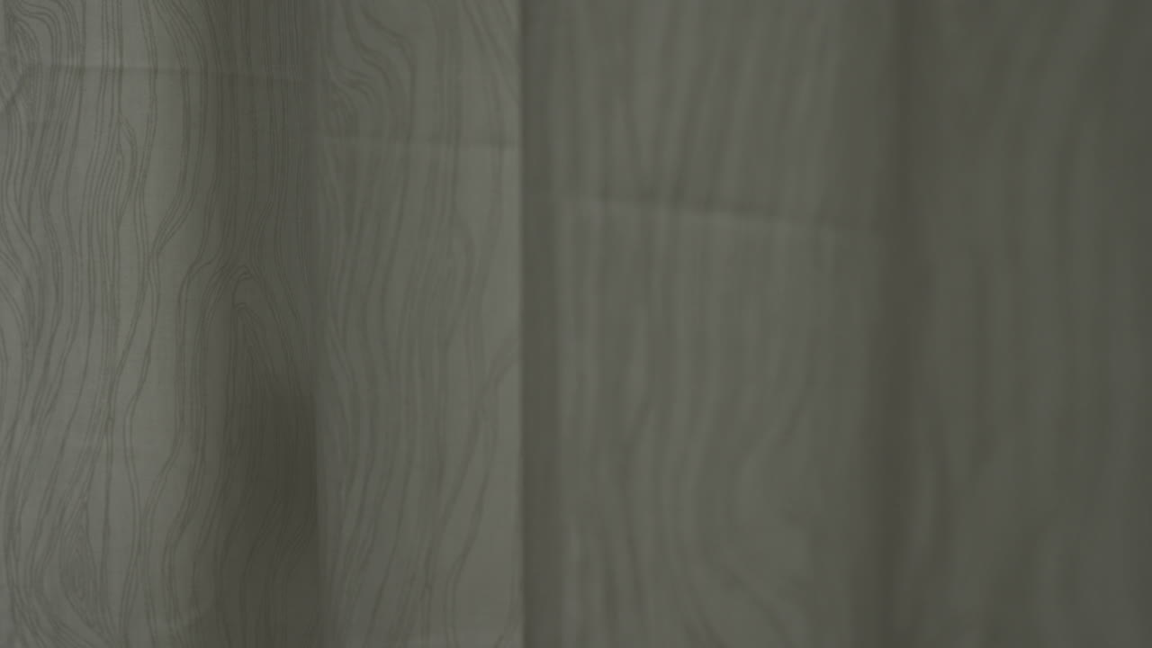 mano cubriendo una puerta o ventana de vidrio con cortinas