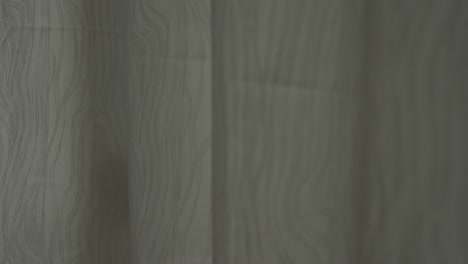 mano cubriendo una puerta o ventana de vidrio con cortinas