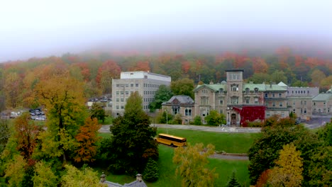 Drone-descending-near-the-Mount-Royal-mountain-showing-an-old-building,-a-school-bus-and-a-spotlight