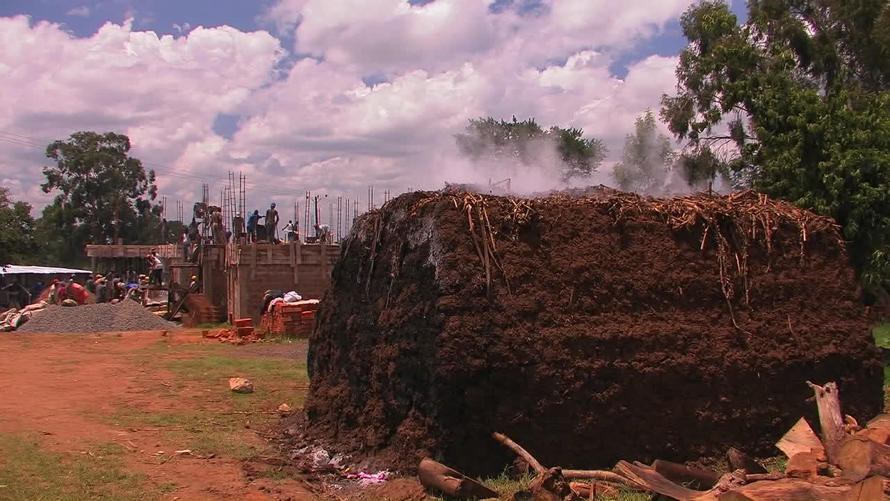 사람들이 건물을 짓고 있고 큰 흙더미에서 증기가 나오고 있습니다.