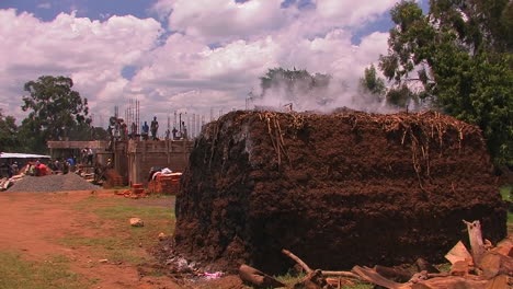 los hombres están construyendo un edificio y sale vapor de una gran pila de tierra