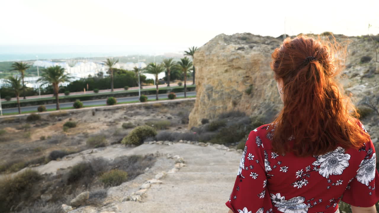 Woman in red dress looking at coastal view