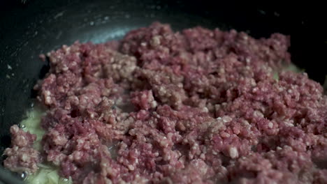 raw mince meat being placed in the pan to cook