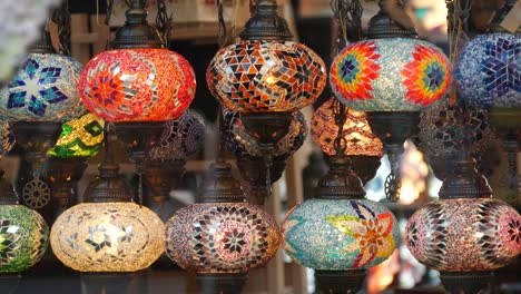 colourful turkish lamps from glass mosaic glowing. arabic multi colored authentic retro style lights. many illuminated moroccan craft lanterns. oriental islamic middle eastern decor. shiny folk shop