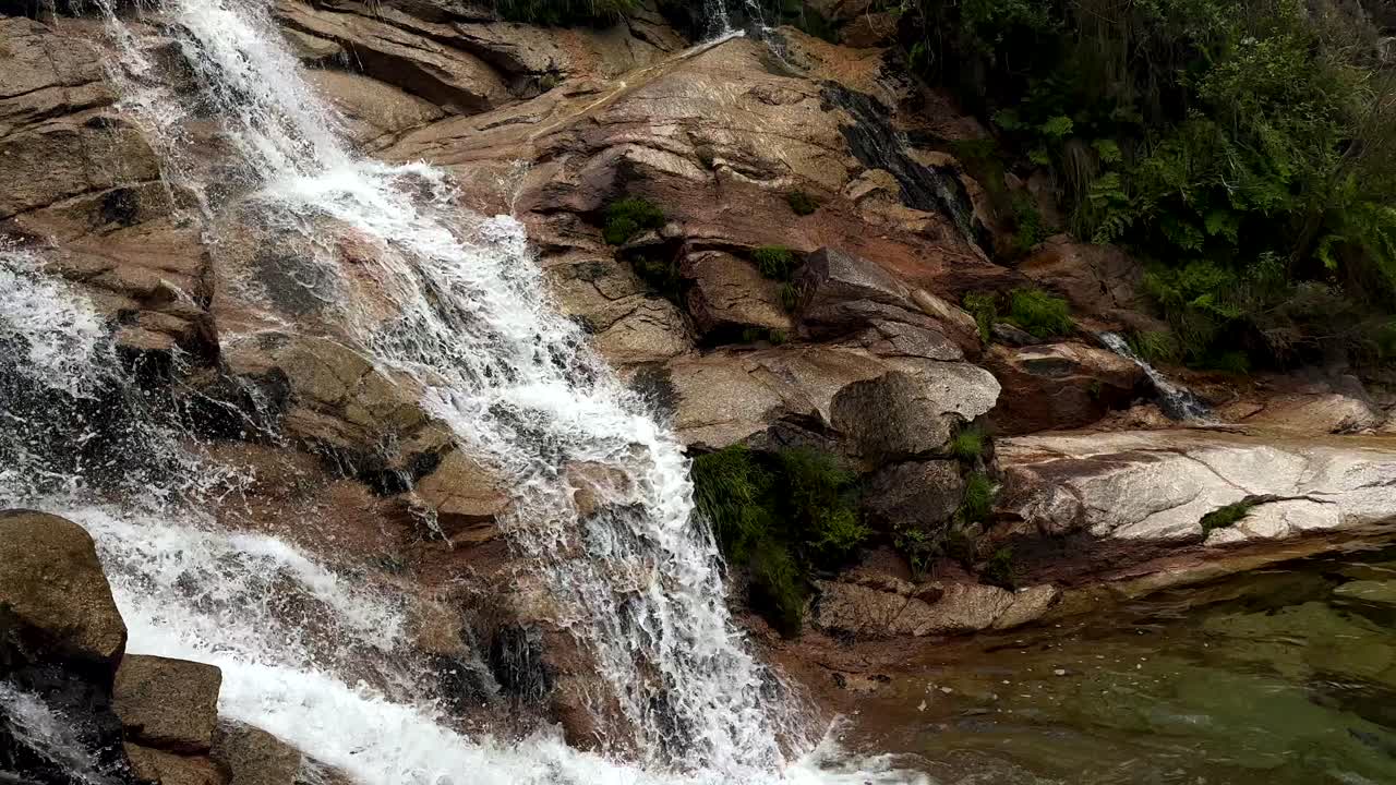 toma en cámara lenta de una cascada en idílico todas las montañas que fluyen en un lago claro - toma panorámica