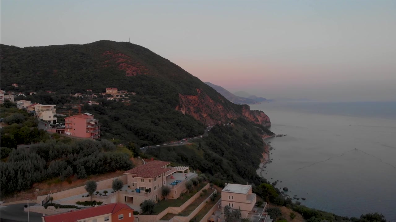 Edifici sul fianco della montagna nel villaggio di Prijevor a Budva, Montenegro, con il Parco Nazionale di Lovcen sullo sfondo. Ripresa aerea con drone.