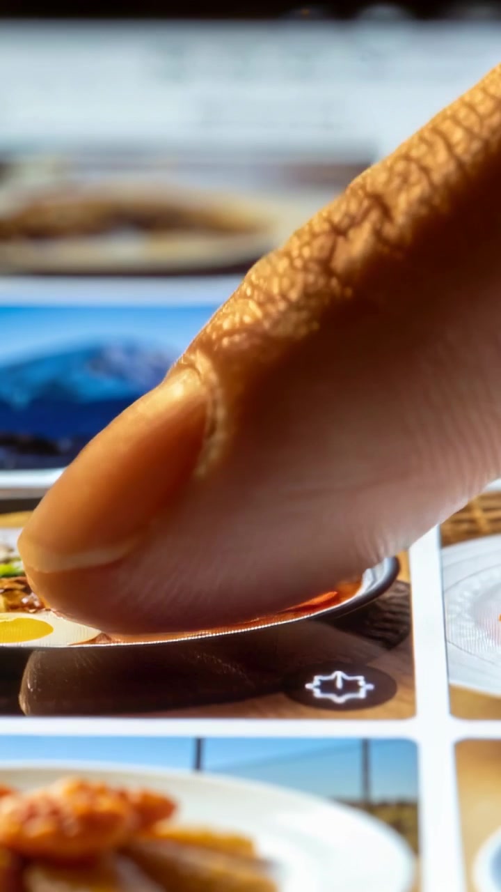Vertical video: Hovering fingertip pressing and sliding on desk screen, browsing soup and mountain
