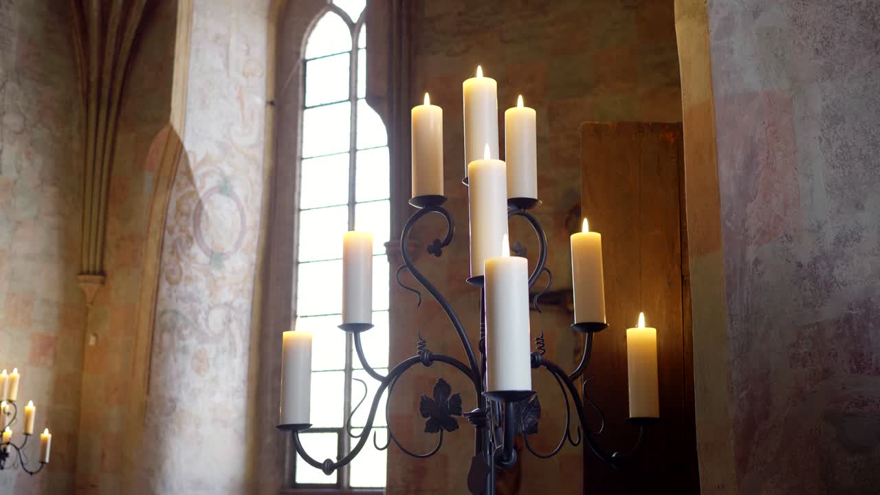 A vintage candle holder with large candles standing in the hall of a Gothic castle