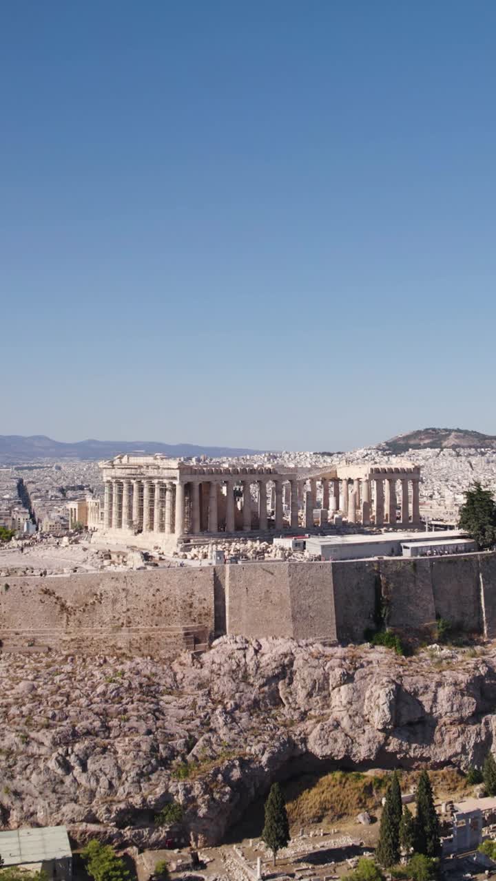 Acropolis in Athens, Greece, standing high above the historical city under a clear blue sky. Aerial, Push Forward, Vertical Video