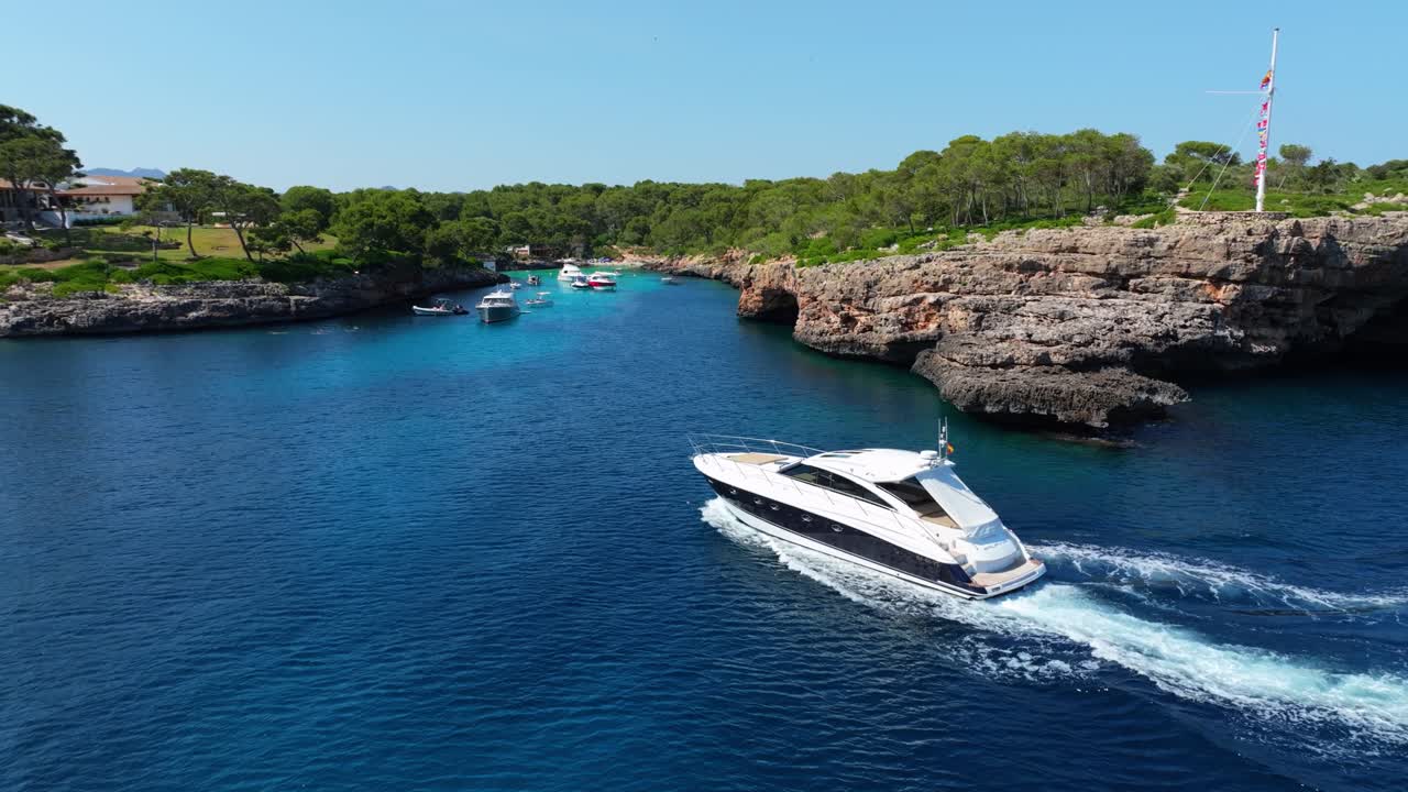 Un lussuoso yacht naviga verso una splendida spiaggia circondata da scogliere a Maiorca in una giornata estiva