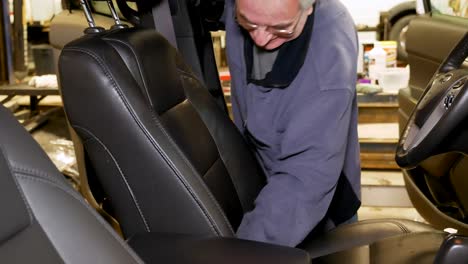 un detallista de un concesionario de automóviles limpia el asiento delantero de un automóvil