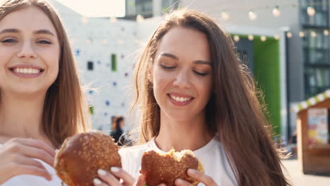 two happy friends eating burgers