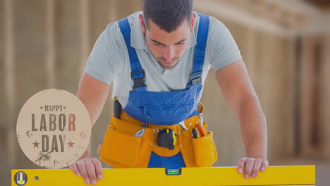 animation of happy labor day text over caucasian worker holding spirit level