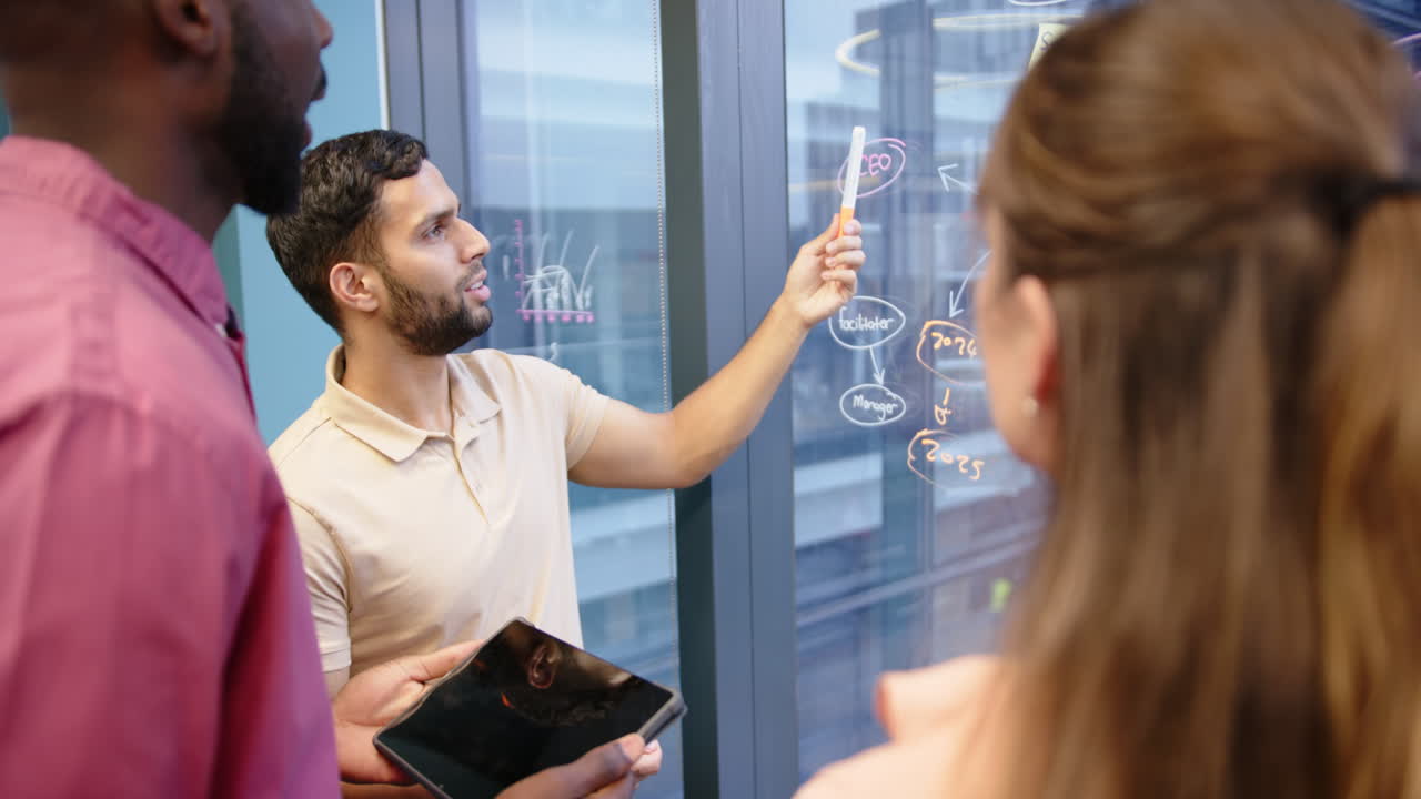 Brainstorming project strategy, team discussing with tablet and glass board in office