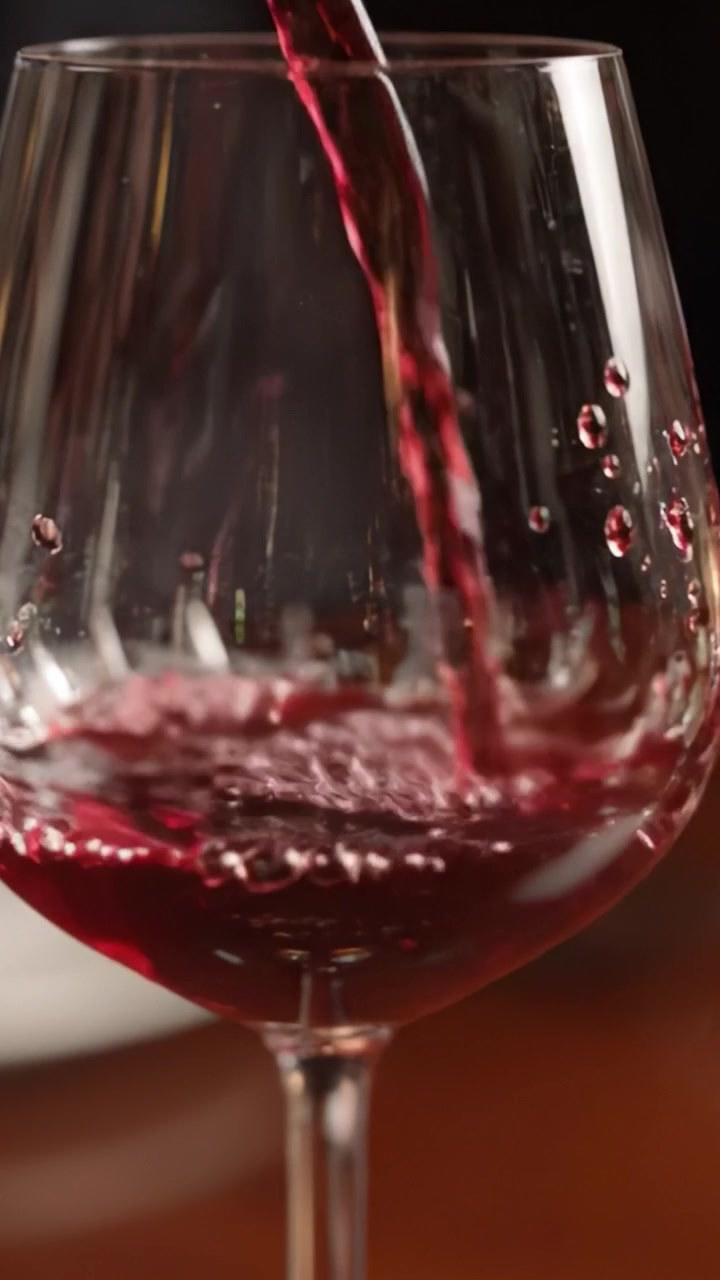 Un viaggio affascinante nel mondo del vino: versando vino rosso in un bicchiere di cristallo che mostra bollicine e colori ricchi.
