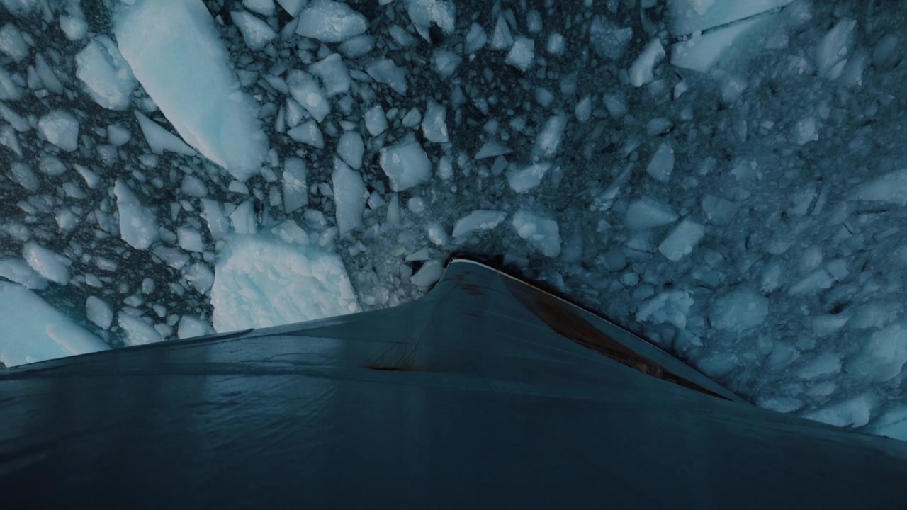 Ship bow cuts through dense drifting sea ice in remote Arctic waters of Greenland.