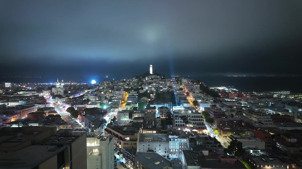 Tågen driver ind over North Beach i en dynamisk time-lapse, delvist indhyller Coit Tower, mens billygterne trækker striber, og nattescenen udvikler sig gennem lag af dis.